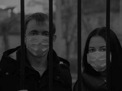A caged masked couple looking worried about the prospect of tackling the coronavirus