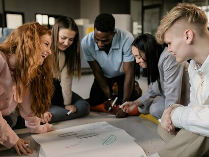 Jovens reunidos discutem ideias e analisam projetos em um ambiente colaborativo. O trabalho do futuro depende cada vez mais da capacidade de construir relações humanas, compartilhar conhecimento e aprender em conjunto