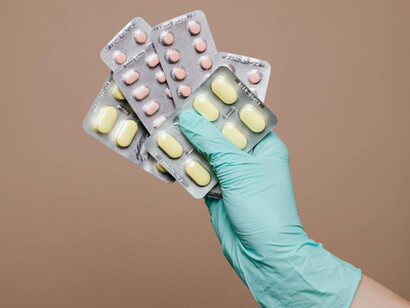 Mano envuelta en un guante quirúrgico sostiene blísteres de medicamentos