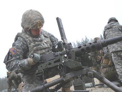 U.S. Army Staff Sgt. Timothy Gibbons, Combined Arms Training Center, 7th Army JMTC, inspects the .50-caliber machine gun for headspace and timing during a familiarization exercise with German soldiers at the Grafenwoehr Training Area, Germany, Dec. 9, 2015