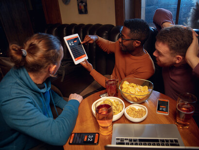 Friends eating snacks, drinking beer and checking sports updates