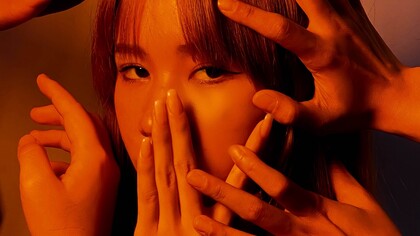 Young girl sadly gazes into the distance as her face is covered by hands