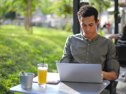 Focused male freelancer working on a laptop at an outdoor caf