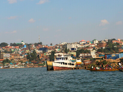 Boats going past the Bukavu city in Congo, representing the enduring impact of extractive economic systems.