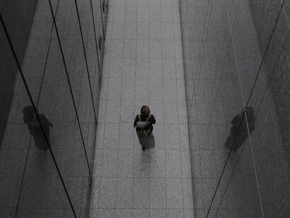 A solitary woman navigating amidst towering buildings, evoking themes of alienation and individuality