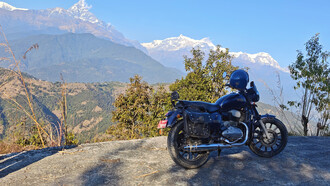 A solitary motorcycle rests quietly before the lush, rolling green mountains of Nepal’s Himalayan landscape