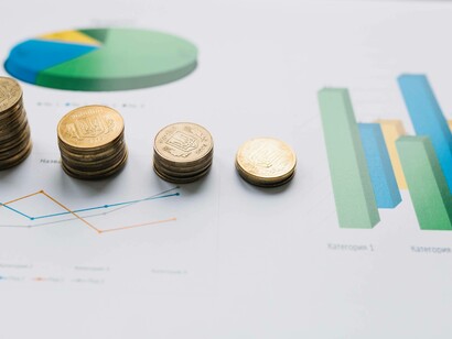 Primo piano di monete impilate su grafici statistici: "Per i prodotti destinati ad una clientela ricca, prodotti alta gamma, prodotti specifici e particolari, già costosi prima negli Stati Uniti, a mio avviso non dovrebbero esserci cali rilevanti nella richiesta"
