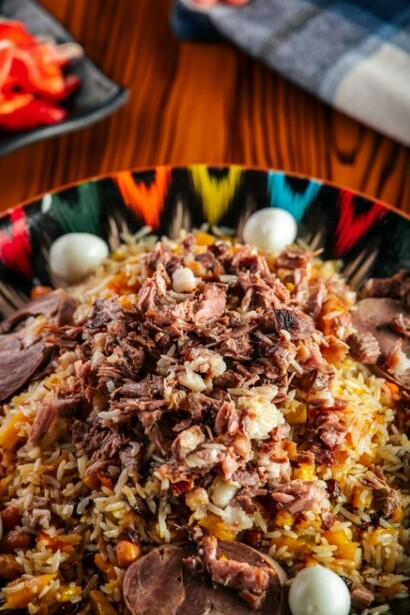Plov, one of the most iconic dishes in Uzbekistan, is beautifully presented on a vibrant plate atop a rustic wooden table