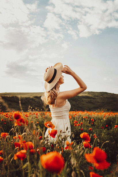 Una mujer contemplando el campo de flores. Descansar y recargar energías nos fortalece mental y emocionalmente