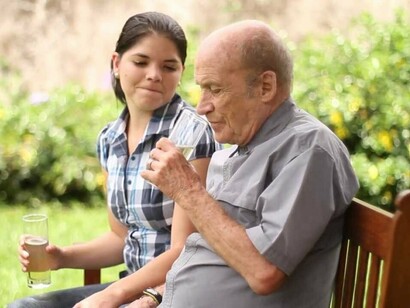 Una cuidadora sentada con un anciano en un banco