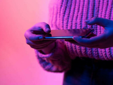 A woman reading the news on her cell phone, engaging in online activism through political memes and viral content