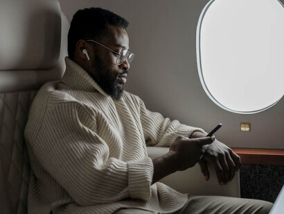 Man sitting on a plane looking at his phone