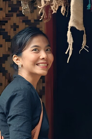 A woman standing in a fabric store, mirroring the Baduy’s devotion to handwoven textiles as carriers of ancestral meaning