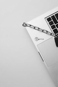Secure your digital fortress with a top view of a laptop shielded by a metal chain and lock, highlighting GDPR compliance amidst the ChatGPT controversy and concerns over data protection authority and privacy breaches
