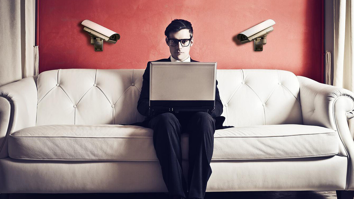 Un hombre sentado en un sofá con su ordenador siendo observado por el mundo
