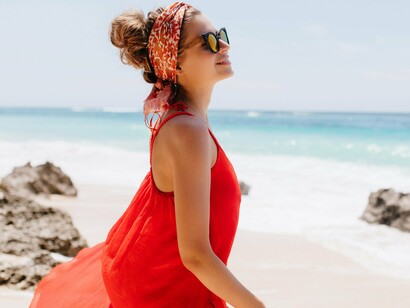 A woman wearing a long, red garment, suggesting a preference for lightweight and breathable fabrics that reflect an adaptation to a warm climate 