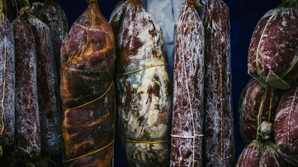Hanging cured meats, suspended in a rustic and artful display, evoke an air of culinary craftsmanship and timeless tradition