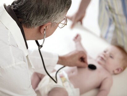 Un pediatra auscultando a un bebé