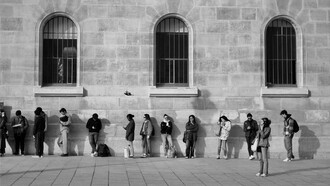 People standing outside a public office with no visible progress, showing the hidden economic cost of lost time
