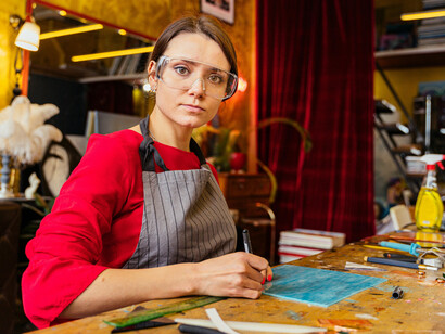 Artist in a studio, painting on a wooden table, hands engaged with material