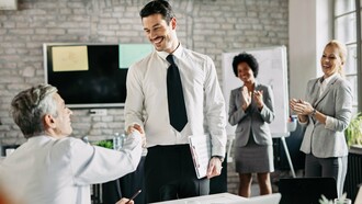 Um aperto de mão que simboliza reconhecimento e parceria, enquanto ao fundo a equipe celebra. Empresas que valorizam seus colaboradores constroem relações mais fortes, produtivas e alinhadas com o bem-estar coletivo