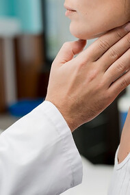 A hand touching the throat of a patient, symbolizing chronic illness, fatigue, exhaustion, and thyroid dysfunction