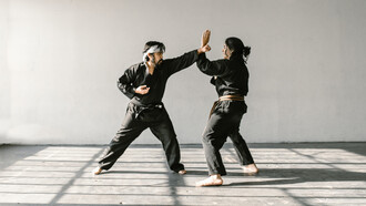 Professor ensina técnica a aluna em aula de defesa pessoal