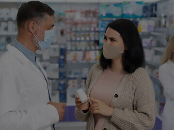 Ein Apotheker, der einem Patienten bei der Abgabe von verschriebenen Medikamenten hilft