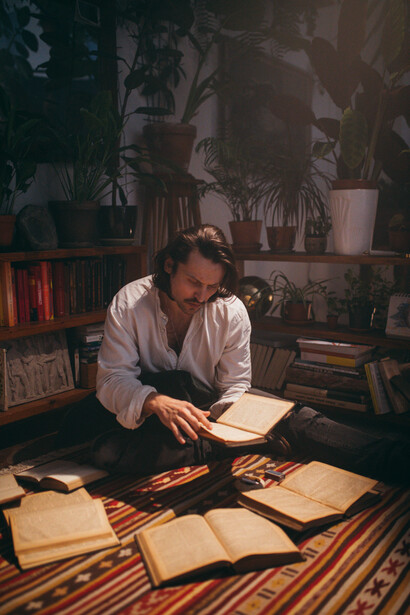 A man reading a book of poetry on a vintage red carpet