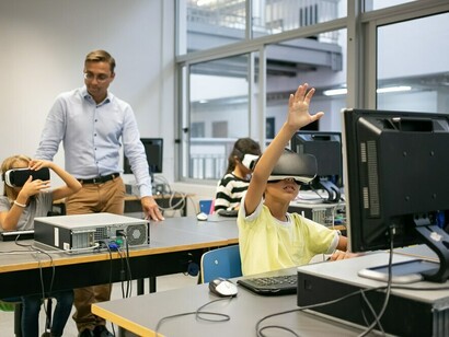 A diverse group of students using VR headsets in a smart classroom, with a teacher guiding them, highlighting the role of AI in education