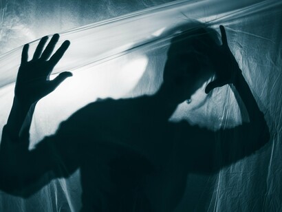 A silhouette presses against a translucent barrier, their features obscured, symbolizing the boundaries between acceptance and otherness, reflecting the struggle of defining humanity versus monstrosity