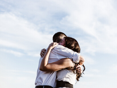 Una pareja se abraza con el cielo azul de testigo