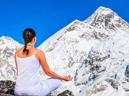 Young woman practising snow yoga in the Himalayas of India, surrounded by breathtaking snowy mountain landscapes