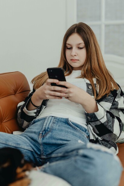 Endless scrolling: a girl reclines on a couch, transfixed by her phone