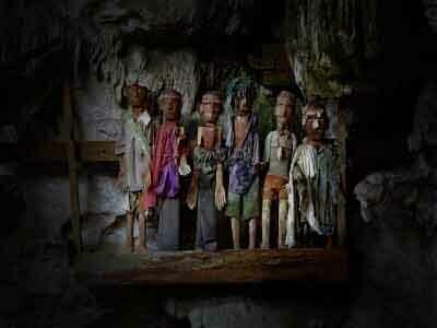 Tau-tau sono statue lignee che riproducono a grandezza naturale le sembianze dei morti che riposano in bare intagliate accatastate più indietro, nel fondo della grotta