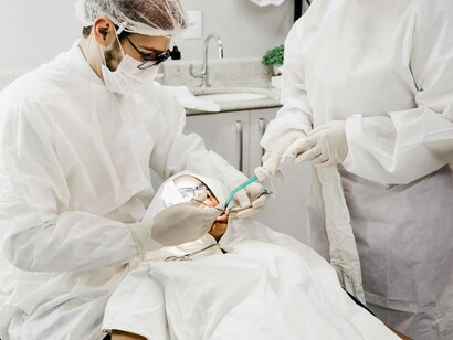 A dentist and his assistant are finishing up a routine dentistry procedure on a calm patient