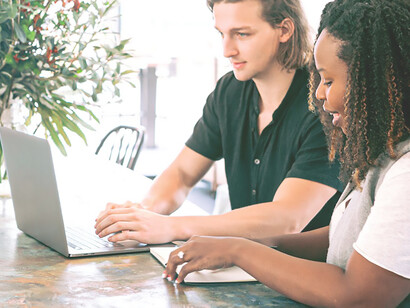 A scene unfolds: a man diligently works on his laptop while a woman takes meticulous notes, capturing the essence of collaborative productivity in action