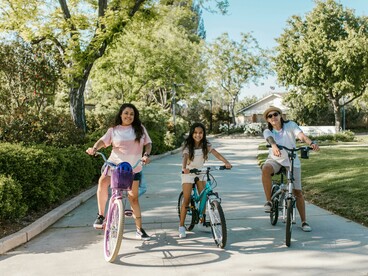 A family rides bicycles in a city park designed for sustainable and pedestrian-friendly living