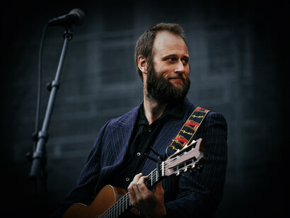 Músico sonríe mientras toca la guitarra. El estilismo de un vistazo cuenta mucho, sin palabras