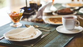 Mesa de café da manhã brasileira com café coada, tapioca, salada de frutas e panqueca