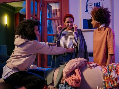 Three friends having fun during a conversation about clothes, symbolising the richness of genuine connection
