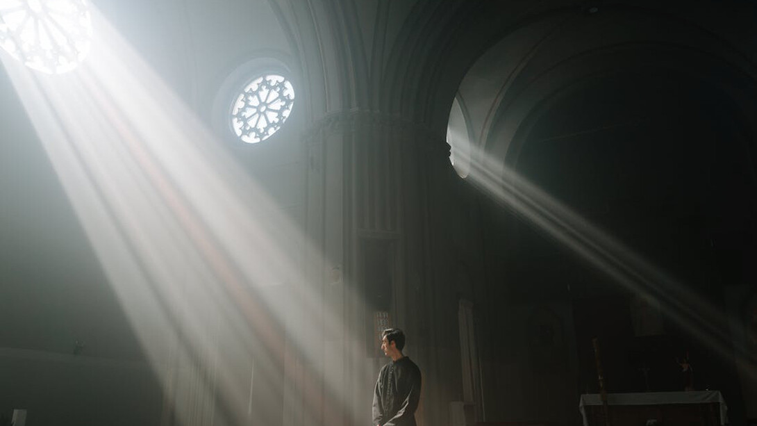 The rays cutting through the darkness serve as a poignant metaphor for the search for truth in a world where faith can be both a refuge and a tool for power