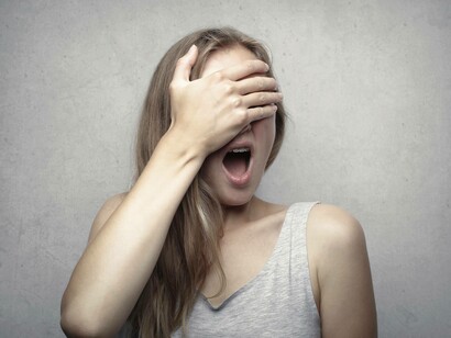 A woman covering her face with her hand of from the fear of the unknown