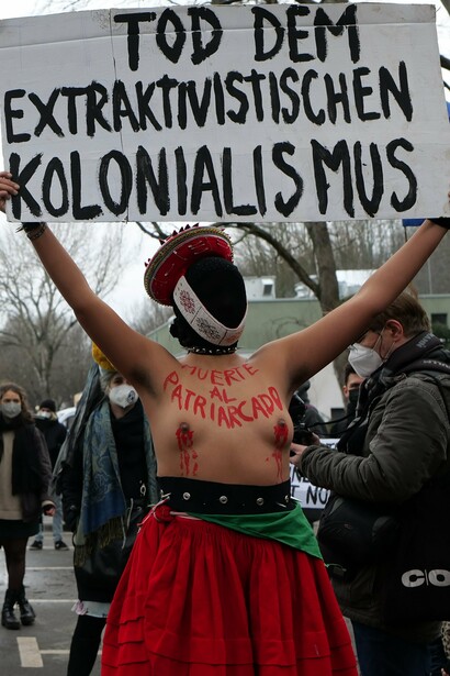 Manifestante sostiene un cartel que dice "Muerte al colonialismo extractivista" durante una marcha en Berlín, Alemania, a raíz de la contaminación producto de la industria petrolera, 2022