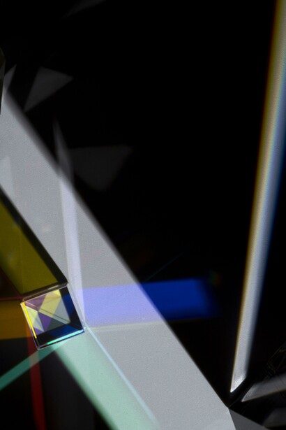 Fascio di luce bianca colpisce un prisma, creando un intenso raggio bluastro