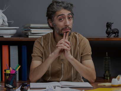 A man, lost in thought and struggling to write at a table, embodies the existential challenges of a disillusioned artist in the literary world
