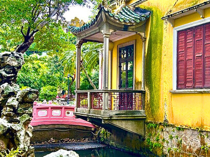 Yellow-facade building connected to the garden by a pastel bridge © Alma Reyes