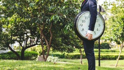 Uomo che tiene sottobraccio un grande orologio: "La saggezza di un tempo ... ci suggerisce di fare -e perseguire- nello stesso fare proprio quello che si sta facendo"