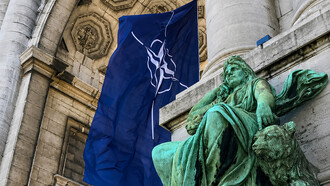 NATO flag displayed beneath the historic arcades of the Cinquantenaire in Brussels, Belgium