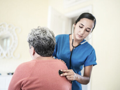 A Latin American woman participates in a home-based medical exam, supported by health and nutrition initiatives in the Global South